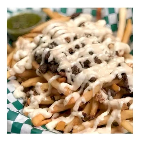 Zait & Za'atar's loaded fries with meat and white sauce, served in a green and white checkered basket.